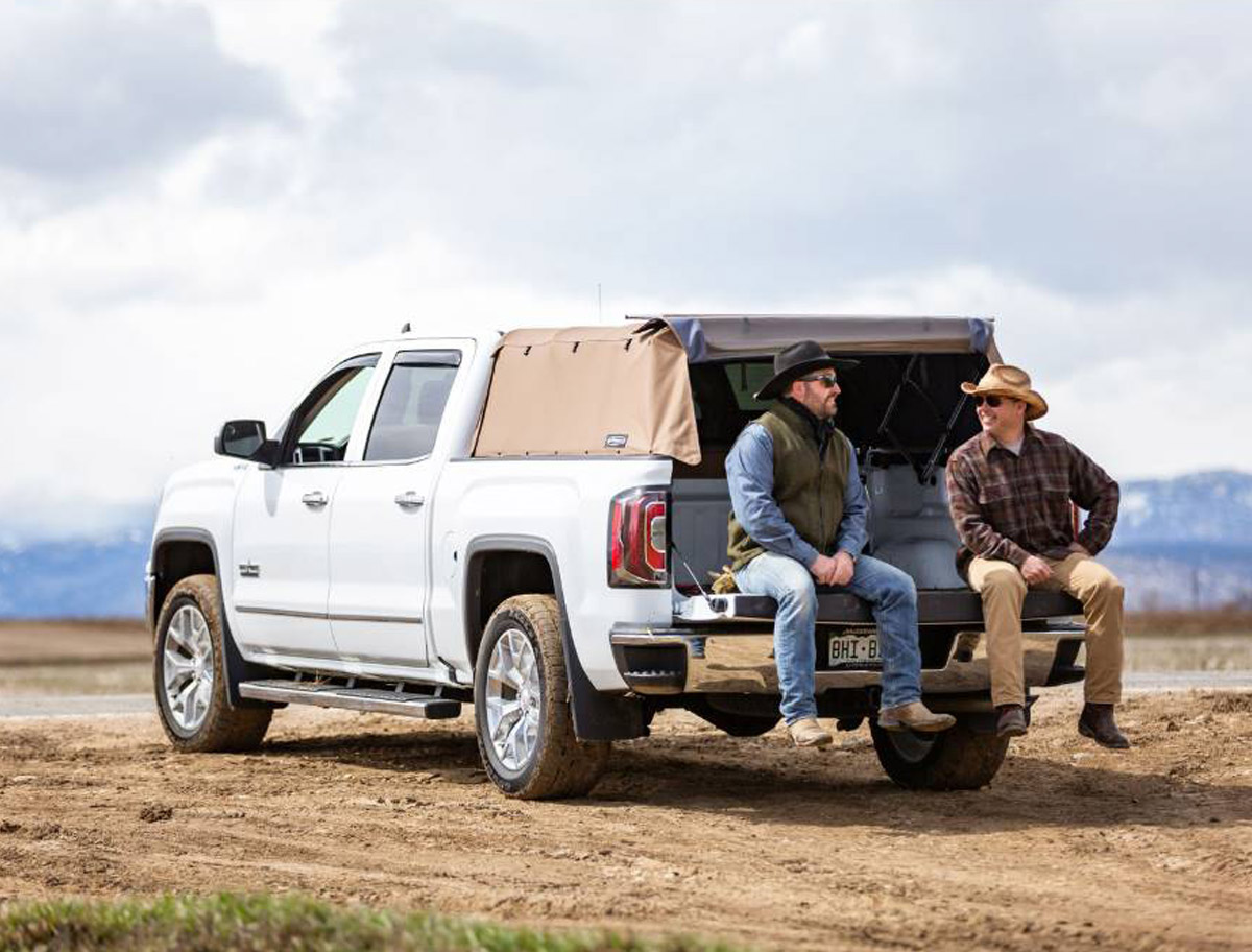 Softopper White GM truck with two ranchers talking sitting on the truck bed